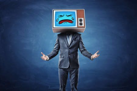 A businessman with hands turned in front of him with palms up and wearing a TV with a sad crying face on his head.の写真素材