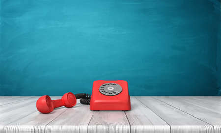 3d rendering of a bright red dial phone standing on a wooden desk and a blue wall background.の写真素材