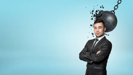 A bearded businessman stands with folded arms while a wrecking ball connects with his head.の写真素材