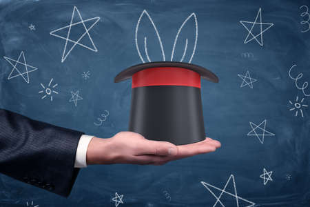 A businessmans palm with a magicians hat resting on it and drawings of stars and rabbit ears around.