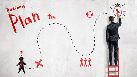 A businessman draws a red and black simplified business plan as a map to success on a white wall.の写真素材