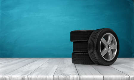 3d rendering of a single car tire leaning on three tires standing on a wooden surface in front of blue background.の写真素材
