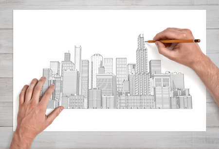Male hands drawing a city crape with many skyscrapers with a pencil on a white paper in close view.の写真素材