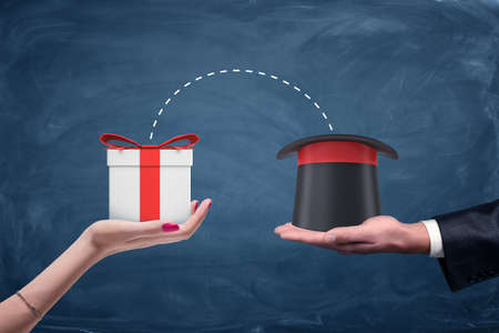 A male businessmans hand holding a wizards hat and a female hand holding a gift box with connecting dots between.の写真素材