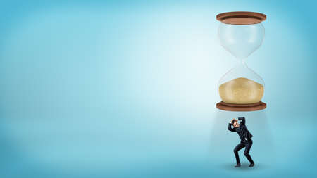 A tiny businessman stands right below a giant hourglass and tries to cover his head.の写真素材