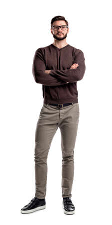 A young man in casual clothing stands with hands crossed in front view on a white background.の写真素材