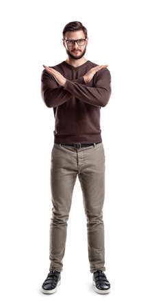 A bearded man in fashionable casual clothes stands with hands making a cross in front of him.の写真素材