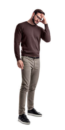 A fashionable man in glasses and casual clothes stands touching his head with one hand in doubt.の写真素材
