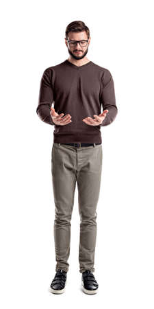 A young bearded man in cargo pants looks down on his both hands cupped as if holding something.の写真素材