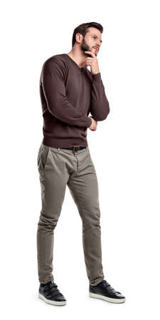 A bearded man in smart casual clothes stands in full height with one hand touching his chin.の写真素材