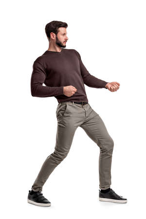 A bearded man a jumper and pants tries to pull a strong invisible rope on a white background.の写真素材