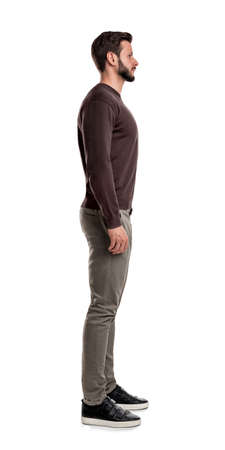 A bearded man in casual clothes stands still with arms hanging straight on his sides in a side view.の写真素材