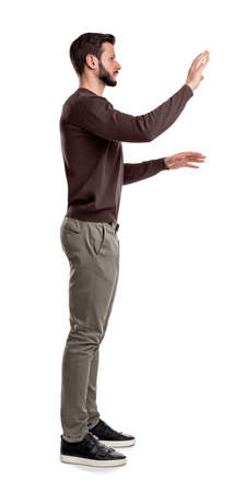 A bearded man in casual clothes stands still in a side view and used both hands to touch invisible digital screen.の写真素材