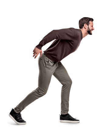 An aggressive bearded man in casual garb stands in a side view and growls or shouts at something.の写真素材