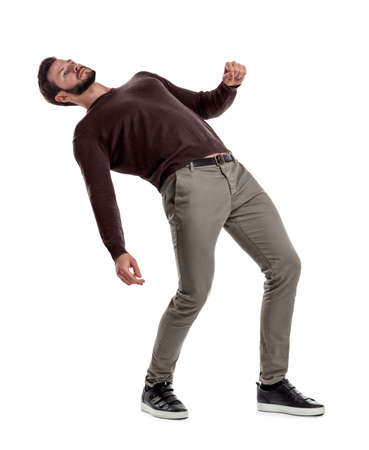 A bearded fit man in casual clothes stands with his back deeply bent backwards on a white background.の写真素材