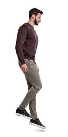 A serious looking bearded man in casual clothes stands in side view as if on a slope.の写真素材