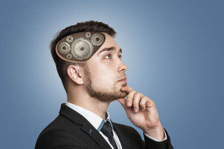 A young serious businessman deep in thought with gears inside his head.の写真素材