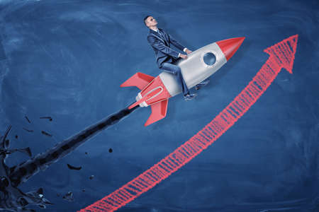 A businessman rides a silver rocket that spurts black oil and flies upwards along a rising arrow.の写真素材