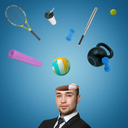 A view of a handsome young mans head cracked open with various sports equipment popping out isolated on blue background.の写真素材