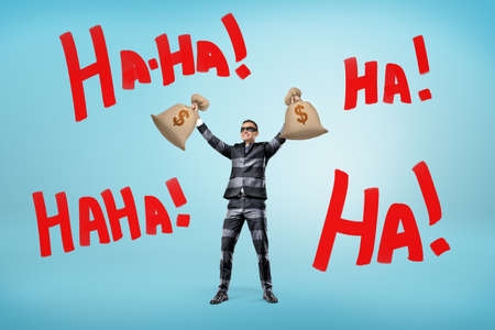 A happy businessman in a striped jail suit and a mask holds money bags above his head near large words Ha-Haの写真素材