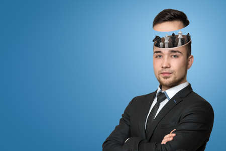 A handsome young man in a suit with head cracked open, and the upper part lifted showing us chess pieces peeking out.の写真素材