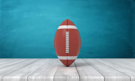 3d rendering of a ball for American football lying on a wooden desk on a blue background.の写真素材