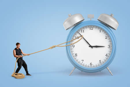 Man pulling clock hands with a rope on blue backgroundの写真素材