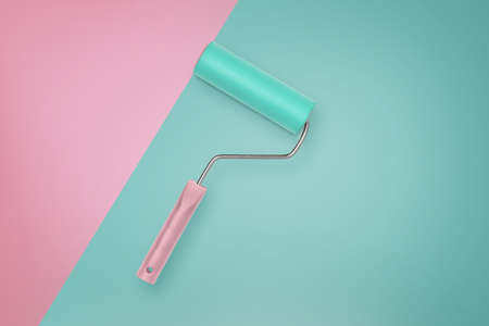 A mint colored paint roller with a pink handle lies on a mint background with a pink section nearby.の写真素材