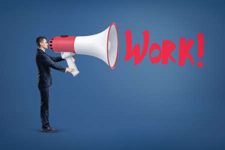 Businessman with big megaphone and red WORK sign on blue background.の写真素材