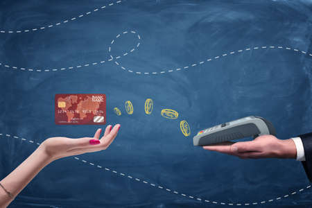 Female hand holding plastic card and male hand holding pin pad on blue background.