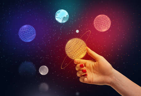 Female hand holding neon Saturn model between fingers with colorful neon planets and outer space on...