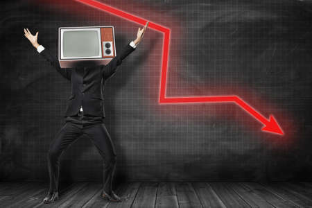 Happy businessman with retro tv set instead of head and red arrow going down on black backgroundの写真素材
