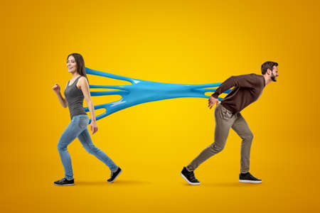 Young brunette girl wearing casual jeans and t-shirt stuck to young man in casual clothes with blue...