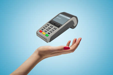 Female hand with PIN pad on blue backgroundの写真素材