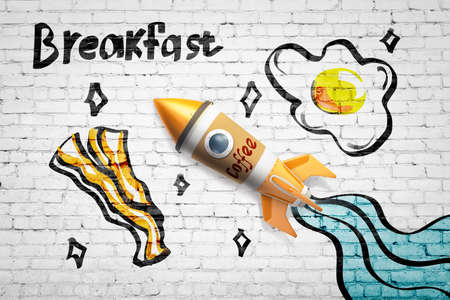 3d rendering of toy rocket made of coffee cup against white brick wall with drawings of eggs and bacon, and title Breakfast.の写真素材