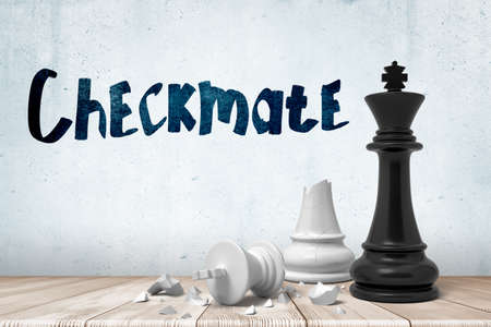 3d close-up rendering of victorious black chess king and defeated broken white king on wooden surface near wall with title Checkmate.の写真素材