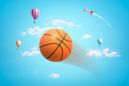 3d rendering of an orange basketball flying in bright blue sky with hot air balloons and rocket in distance.の写真素材
