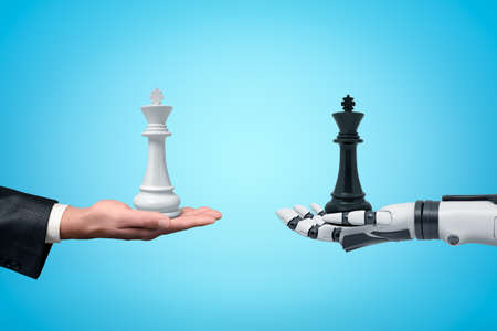 Side view of human hand holding white chess king and android robot hand holding black chess king opposite one another on light blue background.の写真素材