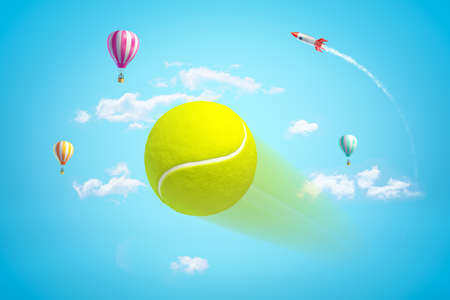 3d close-up rendering of tennis ball flying at full speed in blue sky with hot air balloons and space rocket in distance.の写真素材