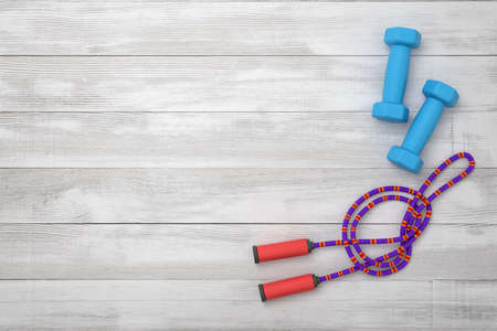 3d rendering of violet jumping rope and blue dumbbells on wooden backgroundの写真素材