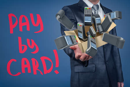 Businessman holding cardboard box filled with PIN pads and Pay by card sign on blue background.の写真素材