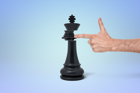 Finger positioned with a black king chess pieceの写真素材