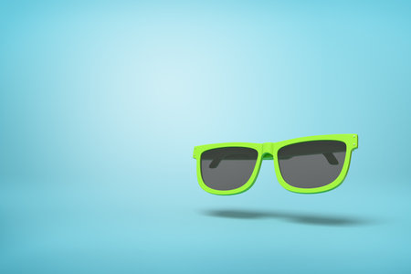 Green sunglasses with ample copy space on blueの写真素材