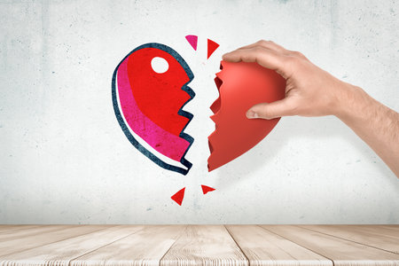Hand holding a broken heart against graphic backdropの写真素材