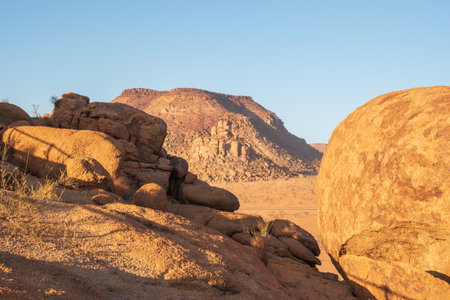 The Namibian desert is home to scattered brown stones and rugged rock formations shaped by natural processes over millennia.の写真素材