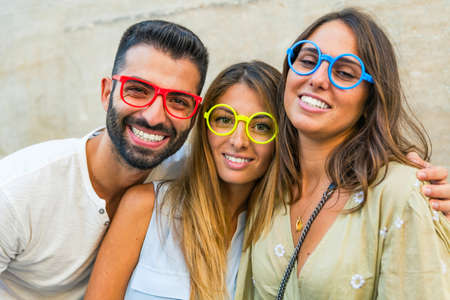 Happy young people holding fake eyeglasses having fun. Photo and carnival funny accessories concept.の写真素材