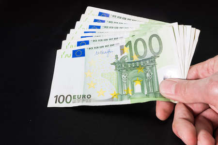 Hand holding banknotes on black
