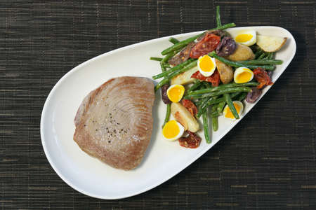 Shot of a meat and salad a white dish on a tableの写真素材