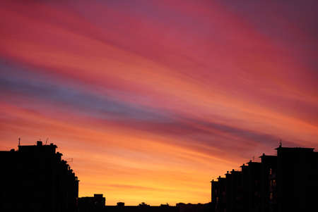 Shot of dark buildings against red dramatic sunset cloudscapeの写真素材