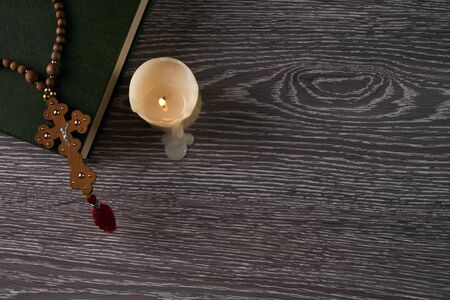 Wood cross, holy bible and candle on wooden table. Religion concept with copy space. Top view